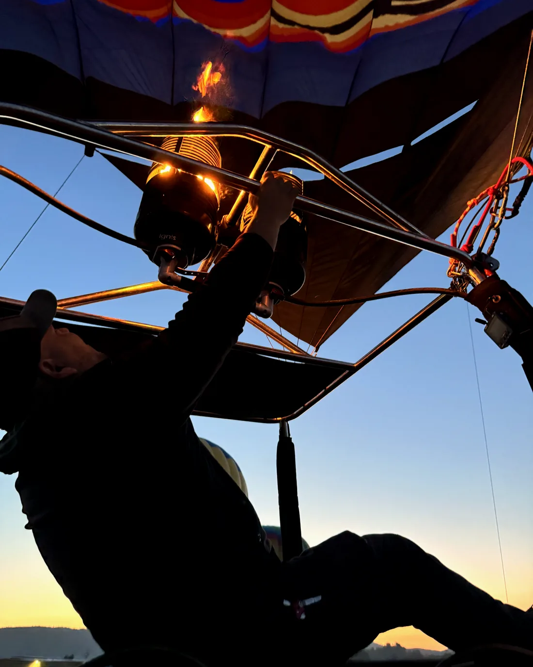 Pilot silhouetted at the burner during a dawn flight
